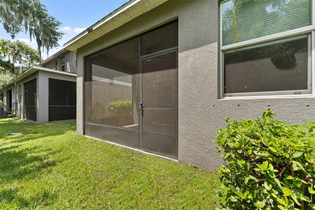 view of property exterior with a yard and a sunroom