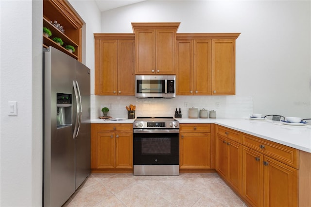 kitchen with light tile patterned flooring, appliances with stainless steel finishes, decorative backsplash, and lofted ceiling