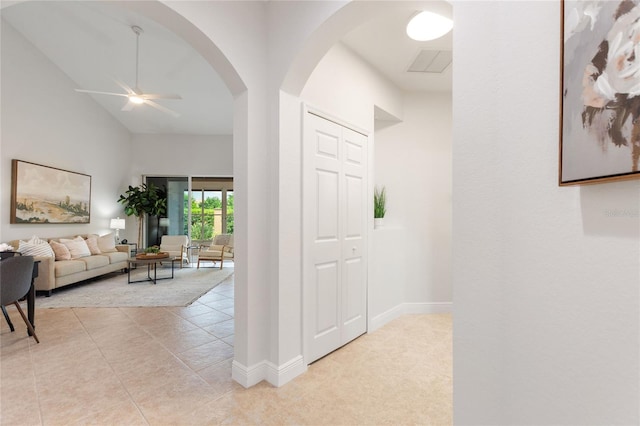 hallway featuring vaulted ceiling and light tile patterned flooring