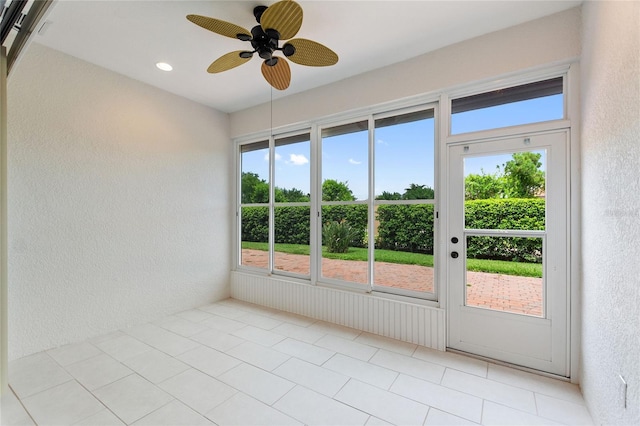 tiled spare room featuring a wealth of natural light and ceiling fan