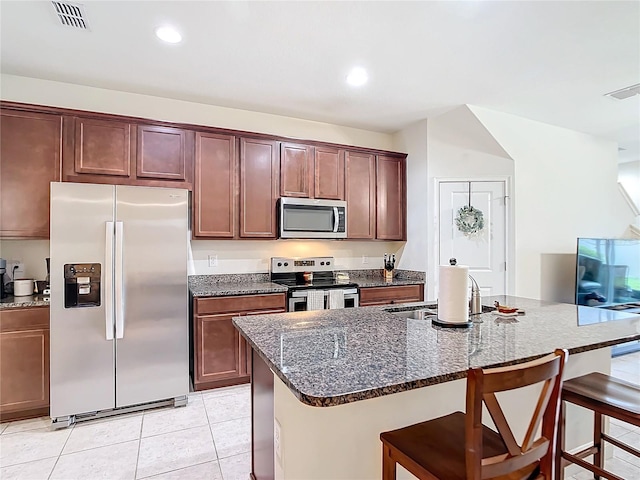 kitchen with sink, appliances with stainless steel finishes, an island with sink, a breakfast bar area, and light tile patterned floors