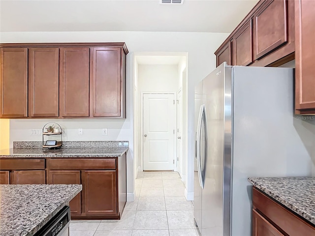 kitchen with light tile patterned floors, dark stone countertops, and stainless steel appliances