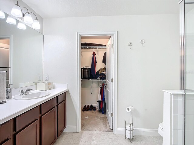 bathroom with toilet, a shower with shower door, and vanity