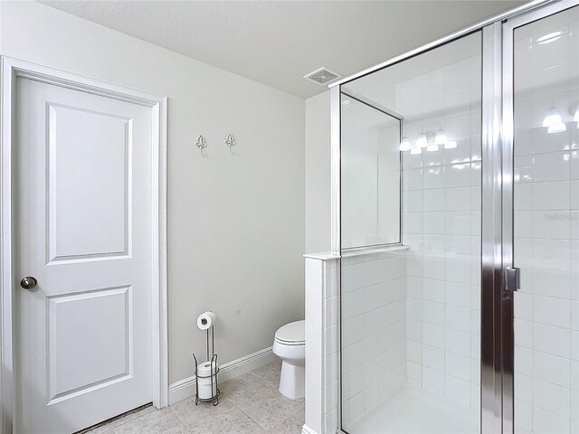 bathroom featuring toilet, tile patterned floors, and a shower with shower door