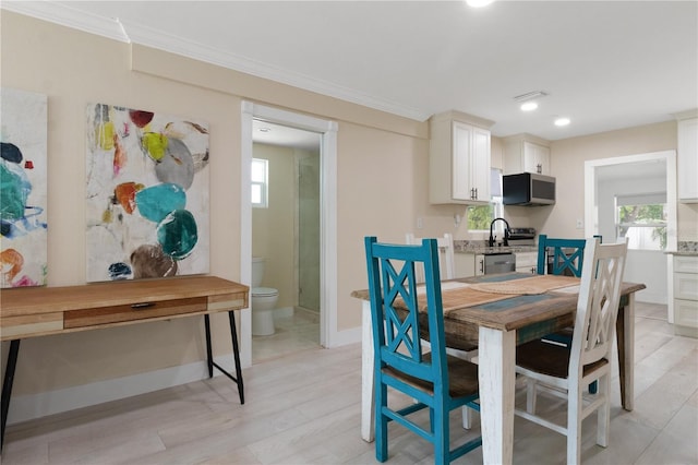 dining space with ornamental molding and light hardwood / wood-style floors