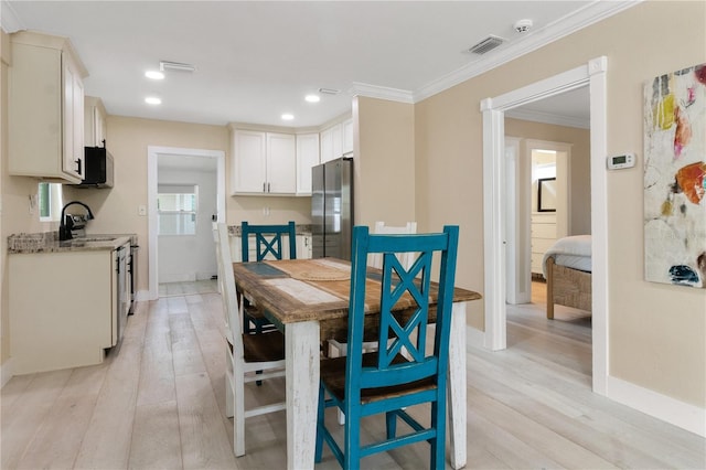 dining space featuring light wood-type flooring and ornamental molding