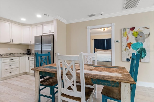 dining room with light wood-type flooring and crown molding