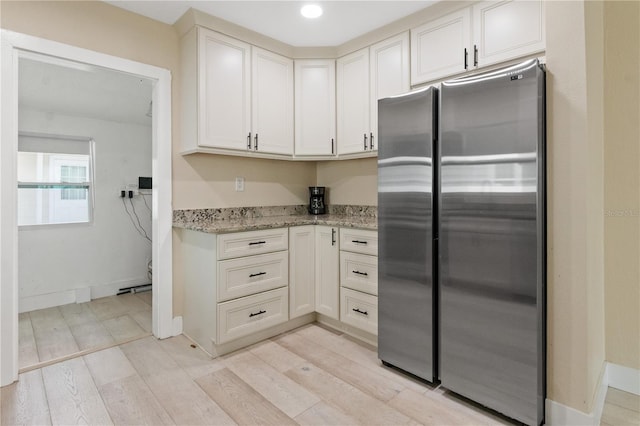 kitchen featuring light stone countertops, light hardwood / wood-style floors, and stainless steel refrigerator