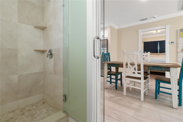 bathroom featuring a shower with door, ornamental molding, and wood-type flooring