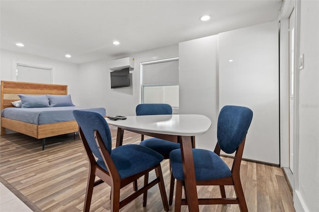 dining space featuring an AC wall unit and light hardwood / wood-style flooring