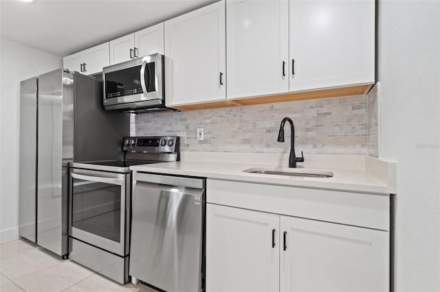 kitchen with appliances with stainless steel finishes, white cabinetry, light tile patterned floors, and sink