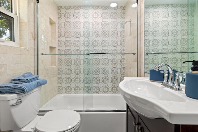 full bathroom featuring tiled shower / bath, vanity, toilet, and tile walls