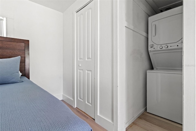 clothes washing area with stacked washer and clothes dryer and light hardwood / wood-style floors