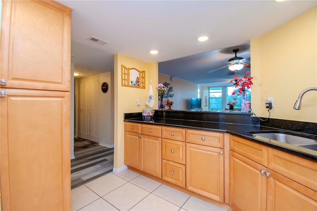 kitchen with ceiling fan, sink, dark stone countertops, and light tile patterned flooring