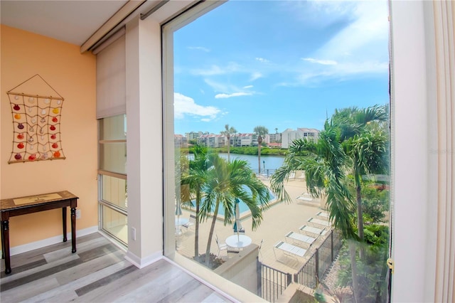 doorway to outside with a water view, wood-type flooring, and a healthy amount of sunlight