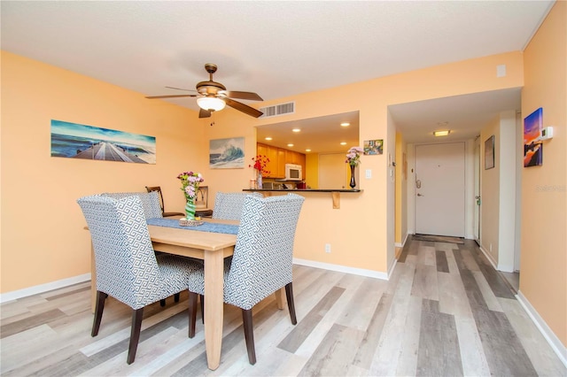 dining room with ceiling fan and light hardwood / wood-style flooring