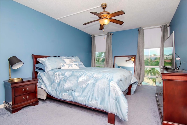 carpeted bedroom featuring multiple windows, a textured ceiling, and ceiling fan