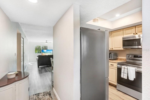 kitchen with appliances with stainless steel finishes, a textured ceiling, light wood-type flooring, and ceiling fan