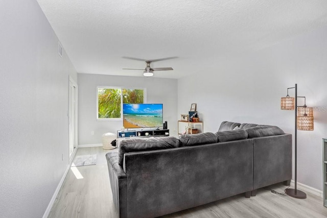 living room with ceiling fan, a textured ceiling, and light hardwood / wood-style flooring