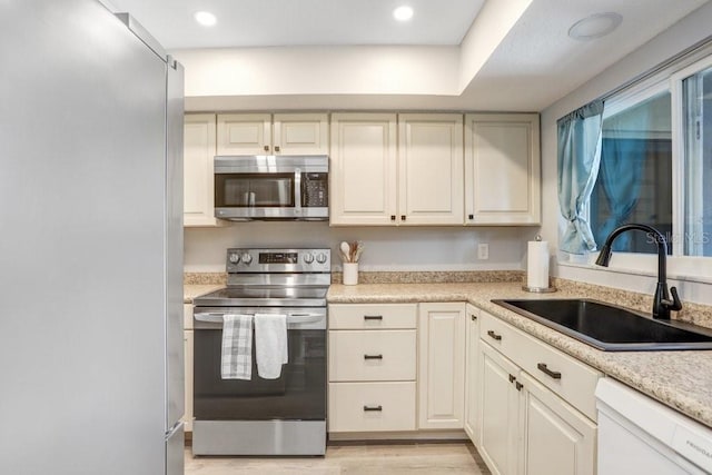 kitchen featuring light hardwood / wood-style floors, stainless steel appliances, light stone countertops, and sink