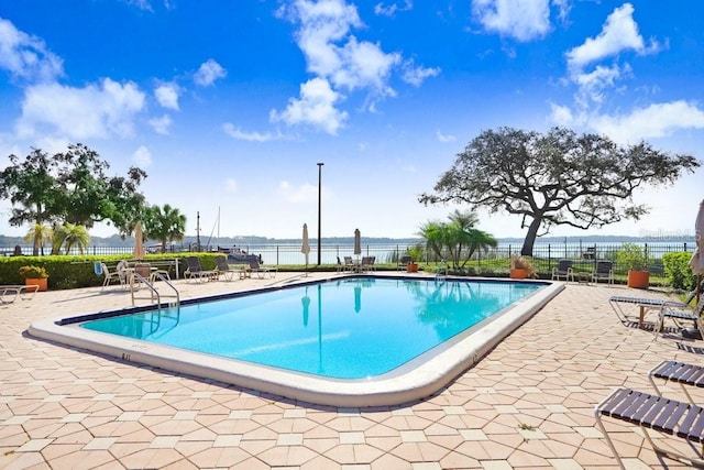 view of pool featuring a water view and a patio area