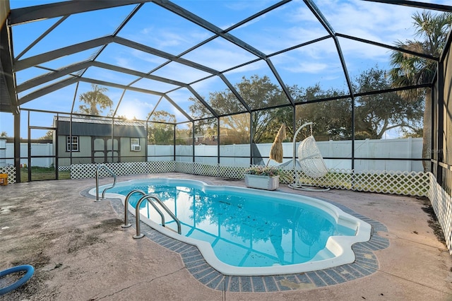 view of pool featuring a patio area, a storage unit, and glass enclosure