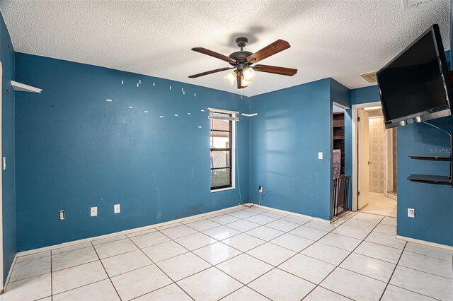 tiled empty room featuring a textured ceiling and ceiling fan