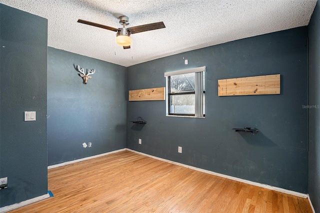 empty room featuring ceiling fan, hardwood / wood-style flooring, and a textured ceiling