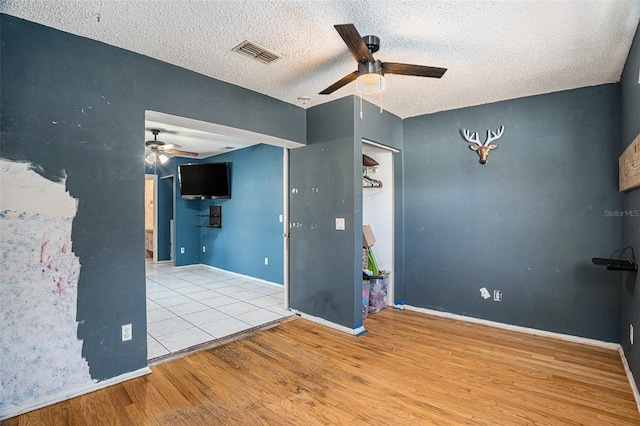 spare room featuring a textured ceiling, light hardwood / wood-style floors, and ceiling fan