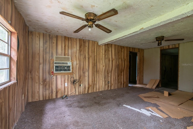 carpeted empty room featuring wood walls, ceiling fan, plenty of natural light, and a textured ceiling