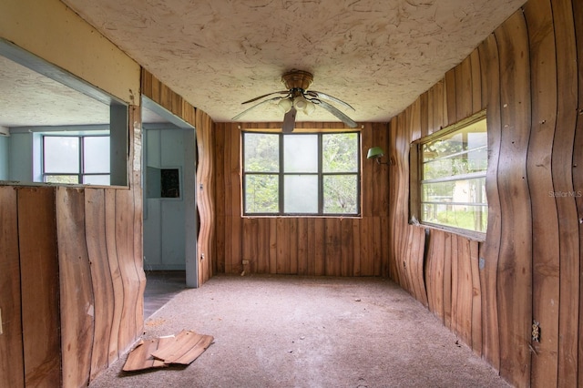 misc room featuring wooden walls, ceiling fan, and carpet