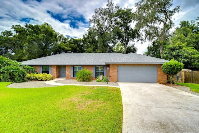 ranch-style house featuring brick siding, concrete driveway, an attached garage, a front yard, and fence