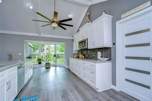 kitchen with white cabinets, light wood-type flooring, appliances with stainless steel finishes, ceiling fan, and decorative backsplash