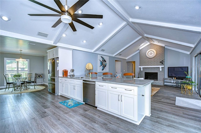 kitchen featuring white cabinets, a brick fireplace, hardwood / wood-style floors, appliances with stainless steel finishes, and ceiling fan