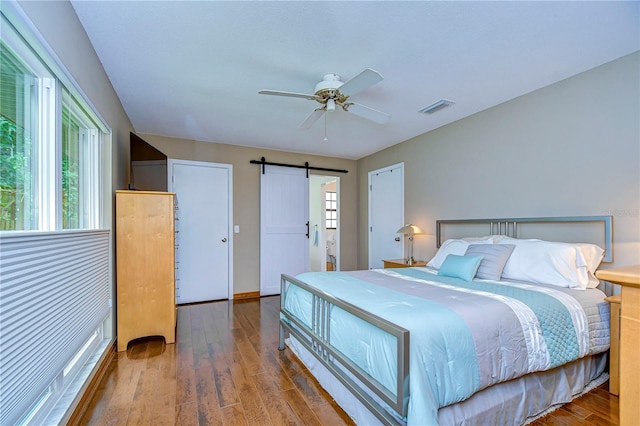 bedroom with a barn door, ceiling fan, and hardwood / wood-style flooring