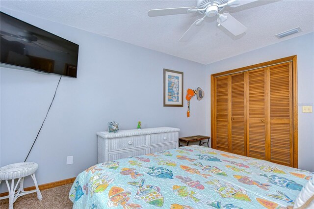 bedroom with a closet, ceiling fan, light colored carpet, and a textured ceiling