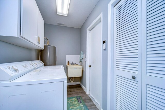 clothes washing area featuring cabinets, water heater, separate washer and dryer, wood-type flooring, and sink