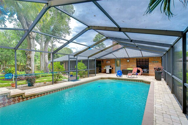 view of pool featuring glass enclosure, grilling area, and a patio area