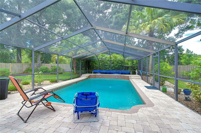 view of swimming pool with glass enclosure and a patio