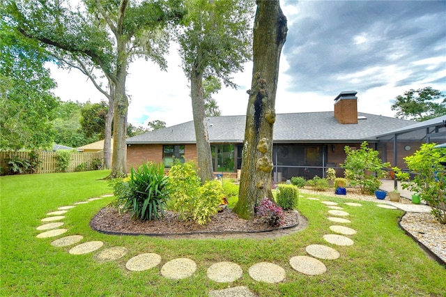 rear view of house featuring a lawn and a sunroom