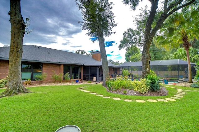 rear view of property with a yard, a lanai, and a swimming pool