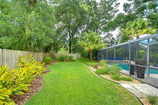 view of yard with a fenced in pool and glass enclosure