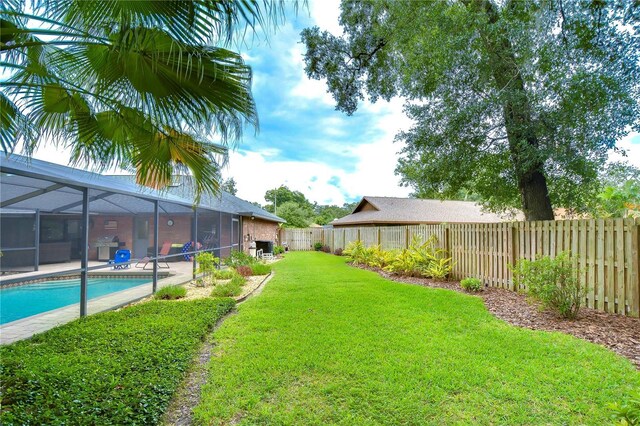 view of yard featuring a fenced in pool and glass enclosure