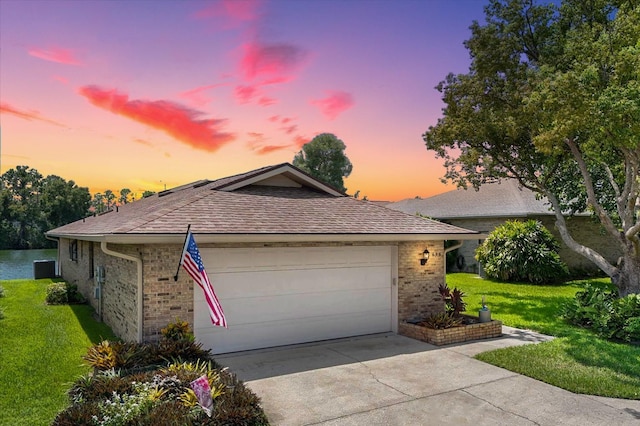 single story home featuring driveway, a yard, roof with shingles, an attached garage, and brick siding