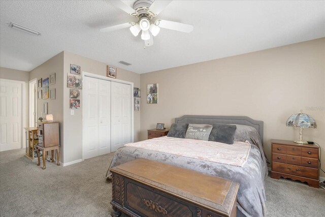 carpeted bedroom featuring a textured ceiling, ceiling fan, and a closet