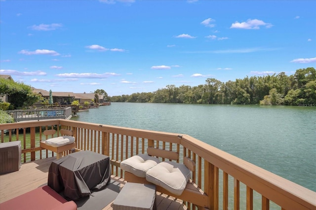 wooden deck featuring a water view and a grill