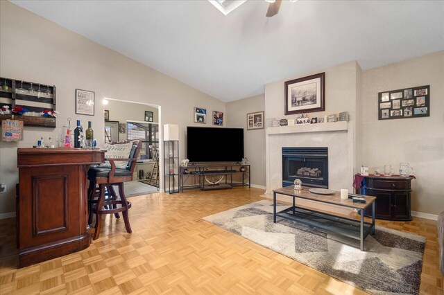 living room with high vaulted ceiling, light parquet flooring, ceiling fan, bar area, and a premium fireplace