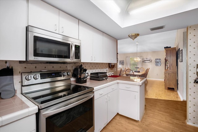 kitchen with appliances with stainless steel finishes, light wood-type flooring, kitchen peninsula, and white cabinetry