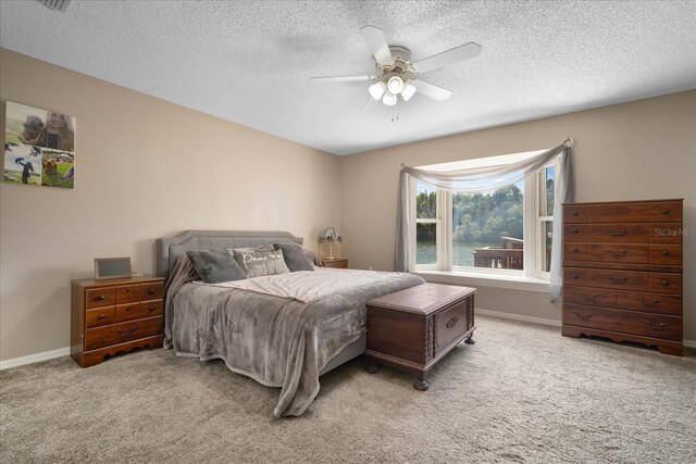 carpeted bedroom featuring ceiling fan and a textured ceiling