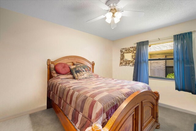 bedroom with ceiling fan, carpet flooring, and a textured ceiling